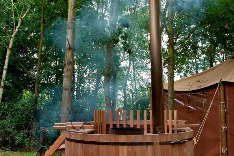 A hot tub with one of the glamping tents