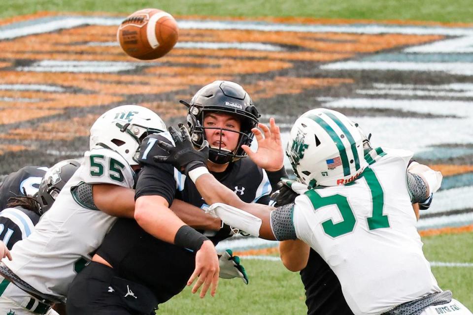 Hough’s Tad Hudson (7) throws while being tackled by Dutch Fork’s Dakota Jordan (55) and Dutch Fork’s Terrance Wells (57) during a game at Memorial Stadium in Charlotte, N.C., Thursday, Aug. 18, 2022.