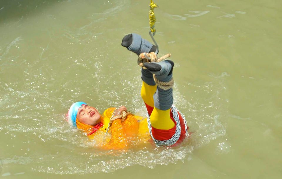 Magician Chanchal Lahiri is lowered into the Hooghly river in Kolkata on Sunday before attempting what would turn out to be his last ever stunt (Picture: Reuters)