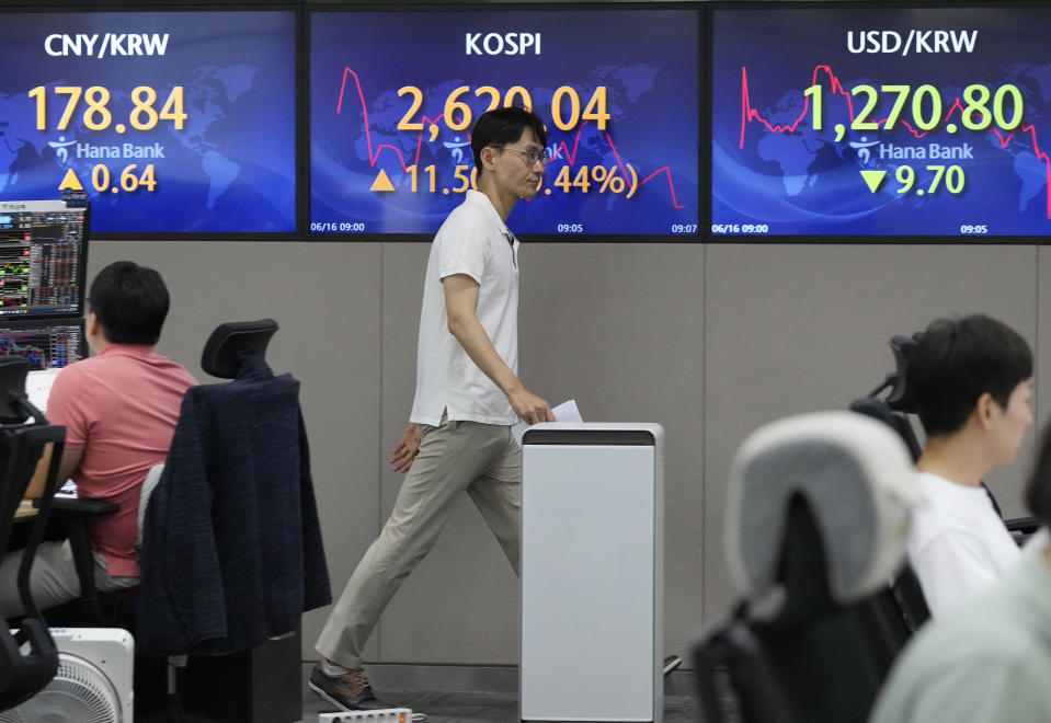 A currency trader passes by the screens showing the Korea Composite Stock Price Index (KOSPI), top center, and the foreign exchange rate between U.S. dollar and South Korean won, top right, at the foreign exchange dealing room of the KEB Hana Bank headquarters in Seoul, South Korea, Friday, June 16, 2023. Asian shares logged moderate gains on Friday after Wall Street benchmarks swept higher, extending their longest rally in a year and a half. (AP Photo/Ahn Young-joon)