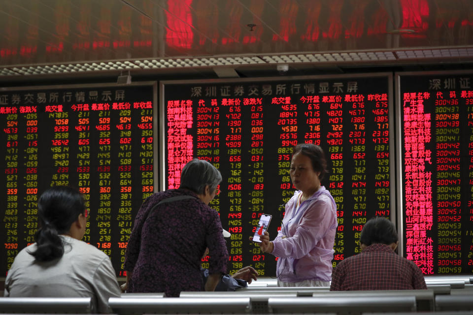 In this Thursday, Sept. 19, 2019, photo, a woman shares a photo on her smartphone with her friends at a brokerage house in Beijing. Asian shares were mostly higher on Friday, Sept. 20, 2019 after a lackluster session on Wall Street, as investors shifted their focus to China-U.S. trade talks after a busy week of central bank news. (AP Photo/Andy Wong)