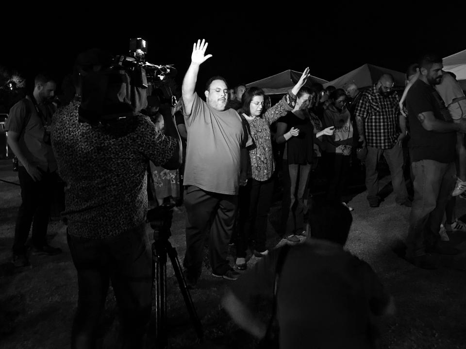 Photographers film a couple praying during a memorial service held Monday night in Sutherland Springs, Texas. (Photo: Holly Bailey/Yahoo News)