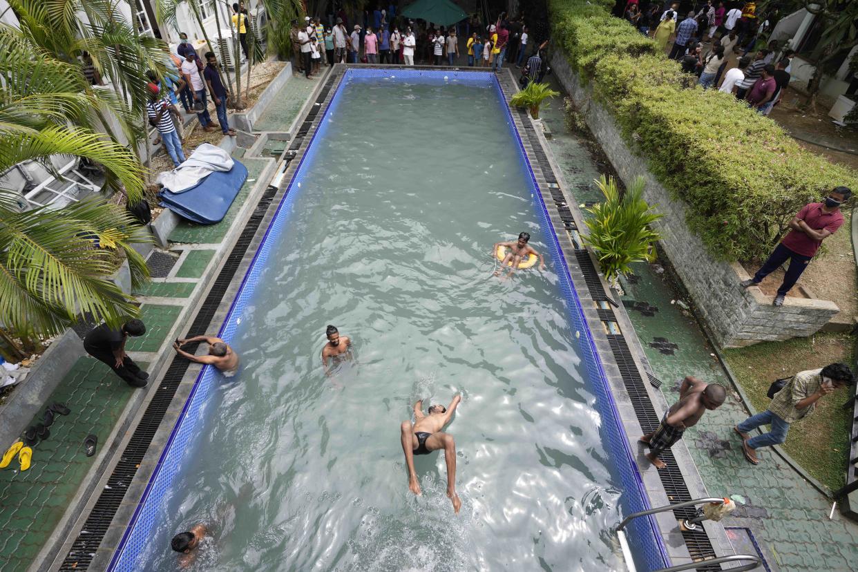 Protesters swim as onlookers wait at a swimming pool in president's official residence a day after it was stormed in Colombo, Sri Lanka, Sunday, July 10, 2022. Sri Lanka’s opposition political parties will meet Sunday to agree on a new government a day after the country’s president and prime minister offered to resign in the country’s most chaotic day in months of political turmoil, with protesters storming both officials’ homes and setting fire to one of the buildings in a rage over the nation’s economic crisis. (AP Photo/Eranga Jayawardena)