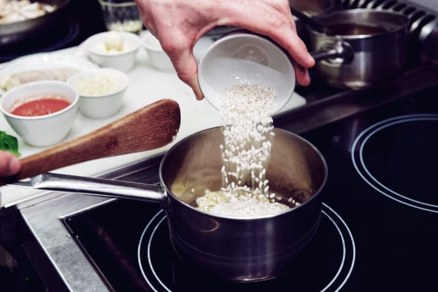 Chef is pouring rice in stewpan