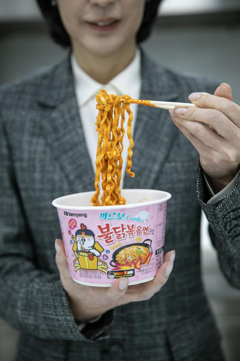 Kim Jung-soo, CEO and Vice Chairperson, prepares to eat "fire chicken noodles" i