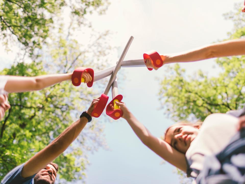 A family playing with foam toy swords in public park together