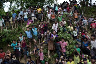 FILE - Rohingya Muslim refugees from Myanmar's Rakhine state stand on a slope and stretch their arms out to receive food being distributed near the Balukhali refugee camp in Cox's Bazar, Bangladesh on Sept. 20, 2017. Ousted Myanmar leader Aung San Suu Kyi is the daughter of the country’s independence hero, Gen. Aung San, who was assassinated in 1947, less than six months before the country, then called Burma, became independent from Britain. Suu Kyi moved to New Delhi in 1960 when her mother was appointed ambassador to India and then spent most of her young adult life in the United States and England. Her career in politics began in 1988. (AP Photo/Bernat Armangue, File)