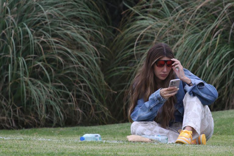 Micaela Tinelli se entretuvo viendo el picadito -y también su celular- desde el césped