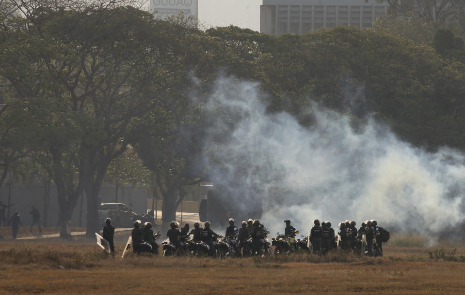 Troops loyal to Venezuela’s President Nicolas Maduro stand amid tear gas they fired from inside La Carlota air base, toward a crowd of a few hundred civilians and a small group of rebel soldiers gathered outside the base in Caracas, Venezuela, Tuesday, April 30, 2019. Venezuelan opposition leader Juan Guaidó took to the streets with activist Leopoldo Lopez and a small contingent of heavily armed troops early Tuesday in a bold and risky call for the military to rise up and oust Maduro. (AP Photo/Fernando Llano)