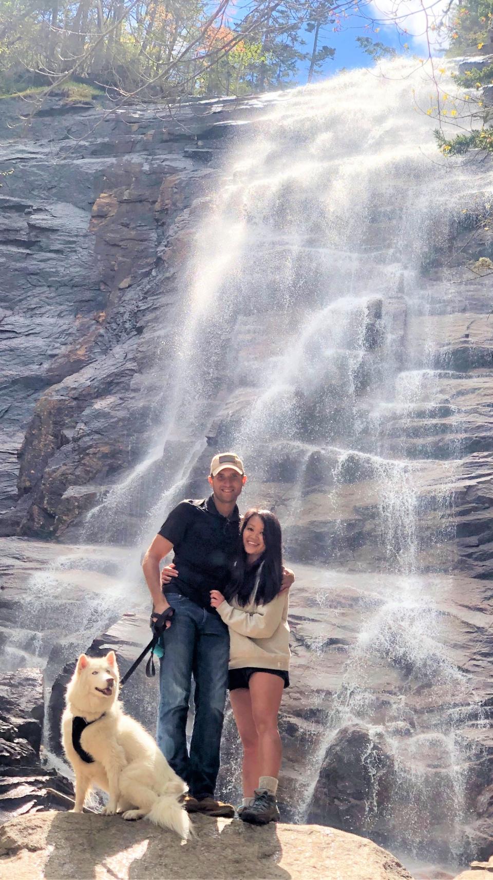Sam Rouabhia, Victoria Lee and Luna, the Siberian husky, on a hike in New England stop by a waterfall.