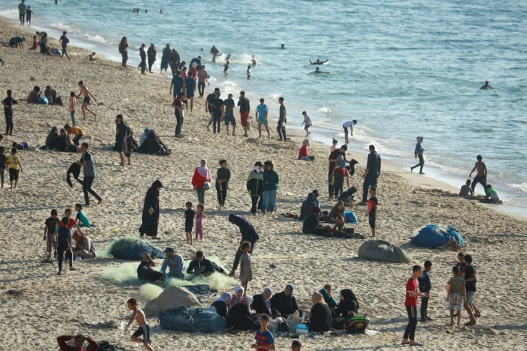 Children paddled in the sea and their friends played ball games on the sand -- but Gaza's war was never far away (-)