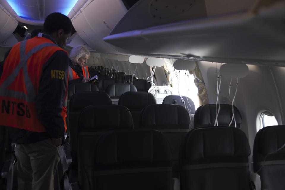 This image taken Sunday, Jan. 7, 2024, and released by the National Transportation Safety Board, investigators examines the frame on a section of Alaska Airlines Flight 1282 that is missing panel on a Boeing 737-9 MAX in Portland, Ore. Federal officials are investigating Boeing's oversight of production of a panel that blew off a jetliner in midflight last week. (NTSB via AP)