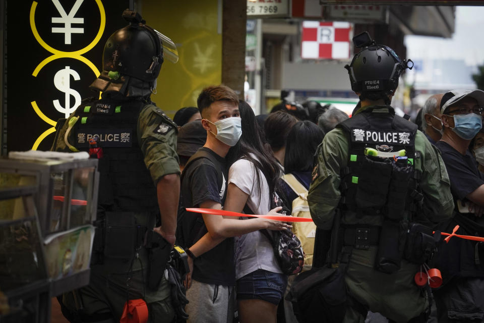 Pedestrians are stopped by police for checking on China's National Day in Causeway Bay, Hong Kong, Thursday, Oct. 1, 2020. A popular shopping district in Causeway Bay saw a heavy police presence after online calls urged people to join protests. (AP Photo/Kin Cheung)