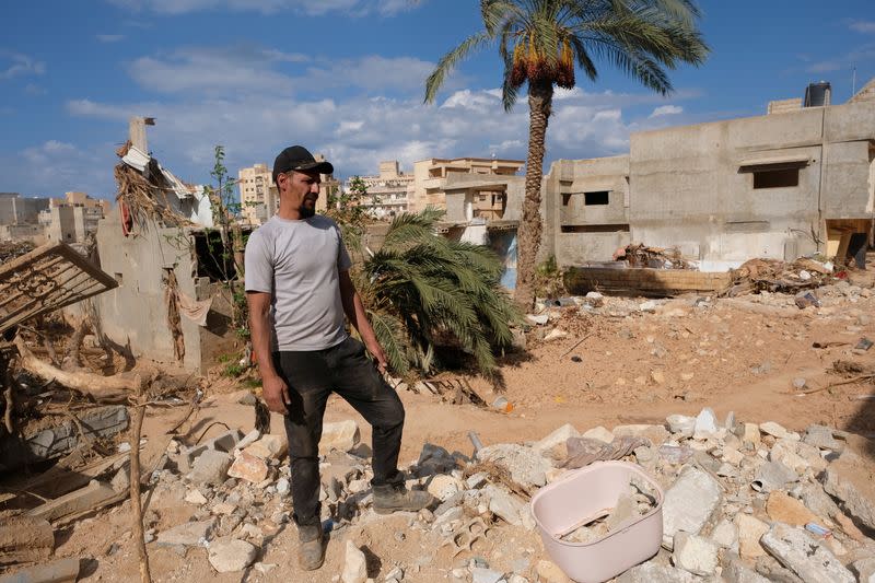 Abdul Salam Ibrahim Al-Qadi, 43 years old, stands on the rubble in front of his house while searching for his father and brother who went missing after the deadly floods in Derna