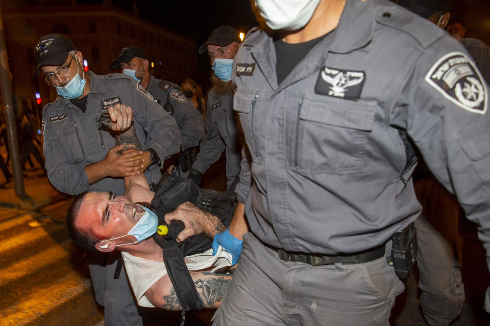 Israeli police officers arrest a demonstrator during a protest against Israel's Prime Minister Benjamin Netanyahu outside his residence in Jerusalem, early Wednesday, July 22, 2020. Protesters demanded that the embattled leader resign as he faces a trial on corruption charges and grapples with a deepening coronavirus crisis. (AP Photo/Ariel Schalit)