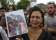 Una mujer con una fotografía de la ex Miss Venezuela Mónica Spear y su ex esposo Henry Thomas Berry durante una manifestación contra la violencia en Caracas, Venezuela, en una fotografía del 8 de enero de 2014. Spear y Berry fueron asesinados en una carretera venezolana y su hija resultó herida en el incidente. (Foto AP/Alejandro Cegarra)