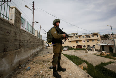 FILE PHOTO: An Israeli soldier stands guard at the scene of an attempted stabbing attack in Hebron, in the occupied West Bank March 12, 2019. REUTERS/Mussa Qawasma/File Photo