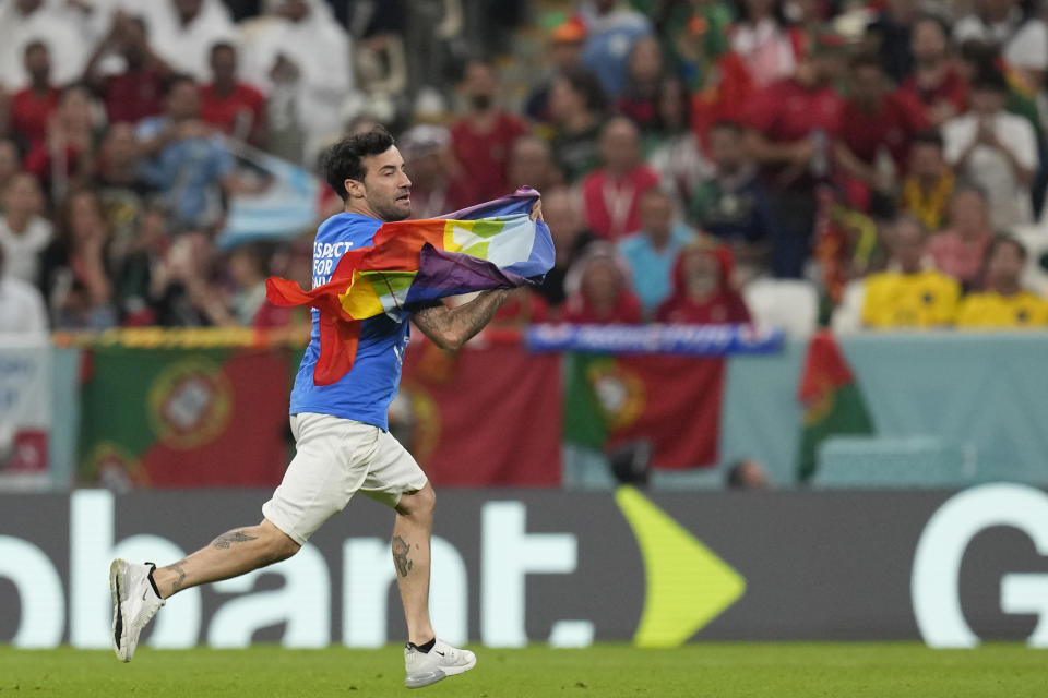 A pitch invader runs onto the pitch with a rainbow flag during the World Cup group H soccer match between Portugal and Uruguay, at the Lusail Stadium in Lusail, Qatar, Monday, Nov. 28, 2022. (AP Photo/Themba Hadebe)