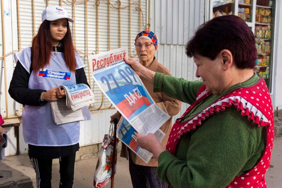 A volunteer of Luhansk regional election commission distributes newspapers to local citizens prior to a referendum in Luhansk People's Republic controlled by Russia-backed separatists on, Sept. 22, 2022.