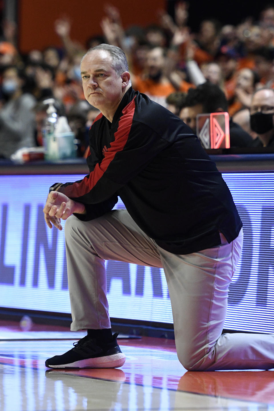 Rutgers coach Steve Pikiell kneels during the first half of the team's NCAA college basketball game against Illinois on Friday, Dec. 3, 2021, in Champaign, Ill. (AP Photo/Michael Allio)