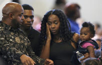 Rev. Jarrett Maupin, left, arrives with Dravon Ames, second from left, Iesha Harper, second from right, and one of the family's two daughters, one-year-old London, right, prior to the start of a community meeting, Tuesday, June 18, 2019, in Phoenix. The community meeting stems from Ames, and his pregnant fiancee Harper having had guns aimed at them by Phoenix police during a response to a shoplifting report after video of their arrest surfaced recently, as well as the issue of recent police-involved shootings in the community. (AP Photo/Ross D. Franklin)