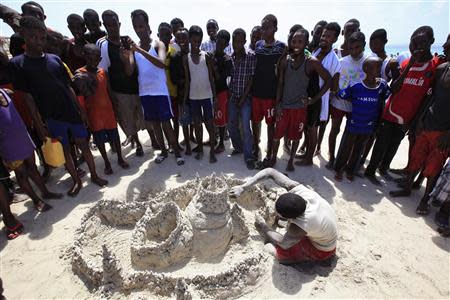 People gather around a man building a sand-castle on Lido beach in Mogadishu October 4, 2013. REUTERS/Omar Faruk