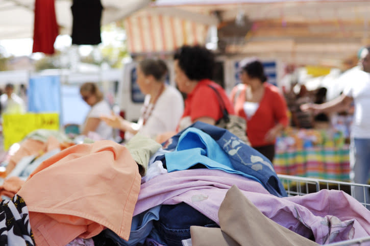 pile of clothes and shoppers in the background