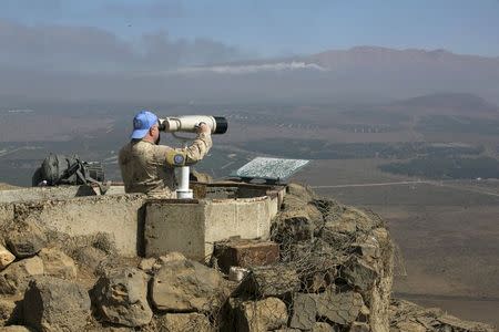 A Canadian member of the United Nations Disengagement Observer Force (UNDOF) looks through binoculars at Mount Bental, an observation post in the Israeli occupied Golan Heights near the ceasefire line between Israel and Syria August 21, 2015. REUTERS/Baz Ratner