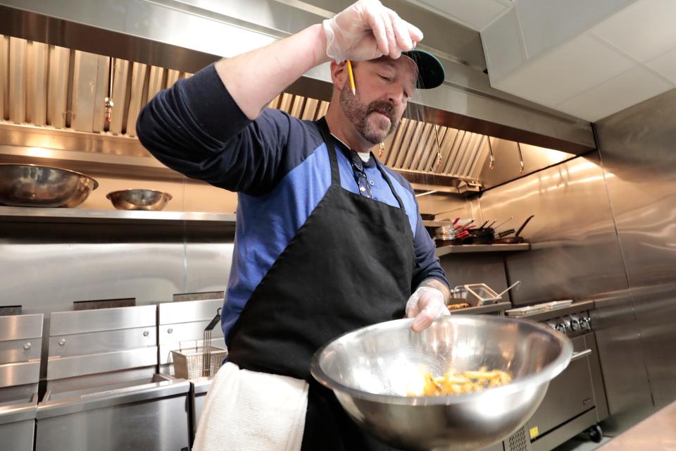 Chef Chris Cronin salts the french fries for the Dirty Fish & Chips he is preparing at the newly opened Union Flats restaurant at 37 Union St. in downtown New Bedford.