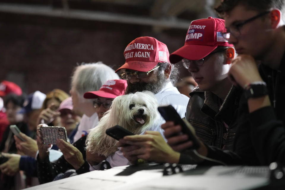 Supporters check their phones as they wait for former President Donald Trump at a campaign stop, Thursday, April 27, 2023, in Manchester, N.H. (AP Photo/Charles Krupa)