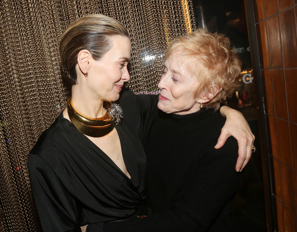 Sarah Paulson and Holland Taylor sharing an affectionate moment, with Sarah wearing a stylish black outfit and gold accessories