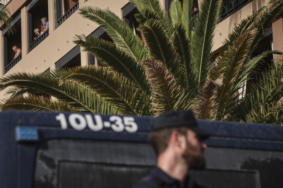 People stand on their balconies of the H10 Costa Adeje Palace hotel in La Caleta, in the Canary Island of Tenerife, Spain, Wednesday, Feb. 26, 2020. Spanish officials say a tourist hotel on the Canary Island of Tenerife has been placed in quarantine after an Italian doctor staying there tested positive for the COVID-19 virus and Spanish news media says some 1,000 tourists staying at the complex are not allowed to leave. (AP Photo)