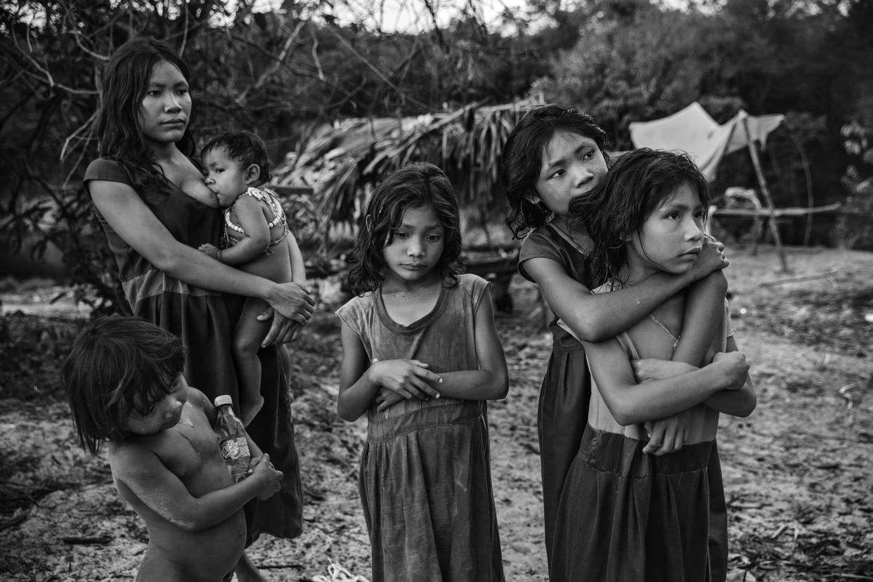 This image provided by World Press Photo, part of a series titled Amazonian Dystopia, by Lalo de Almeida for Folha de Sao Paulo/Panos Pictures which won the World Press Photo Long-Term Project award, shows Women and children from the Piraha community, standing next to their camp on the banks of the Maici River, watch drivers passing by on the Trans-Amazonian highway hoping to be given snacks or soft drinks, Humaita, Amazon, Brazil, Sept. 21, 2016. (Lalo de Almeida for Folha de Sao Paulo/Panos Pictures/World Press Photo via AP)