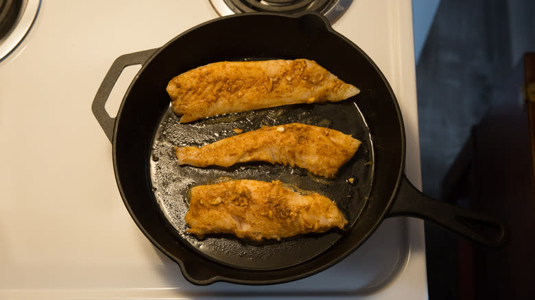 cod frying in black pan 