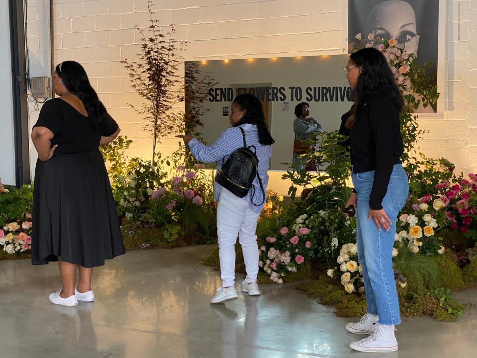 Artists Lauren Palmer, left, and her sister Callie Palmer, right, show guests the Send Flowers to Survivors floral installation they created as part of their studio The Wild Mother.