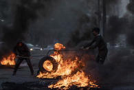 An anti-government protesters burns tires to block a road, during a protest in Beirut, Lebanon, Tuesday, March 2, 2021. Scattered protests broke out in different parts of Lebanon Tuesday after the Lebanese pound hit a record low against the dollar on the black market, a sign of the country's multiple crises deepening with no prospects for a new Cabinet in the near future. (AP Photo/Hassan Ammar)