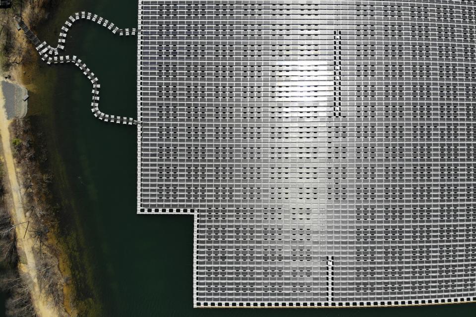 An array of solar panels float on top of a water storage pond in Sayreville, N.J., Monday, April 10, 2023. Floating solar panel farms are beginning to boom in the United States after rapid growth in Asia. They're attractive not just for their clean power and lack of a land footprint, but because they also conserve water by preventing evaporation. (AP Photo/Seth Wenig)