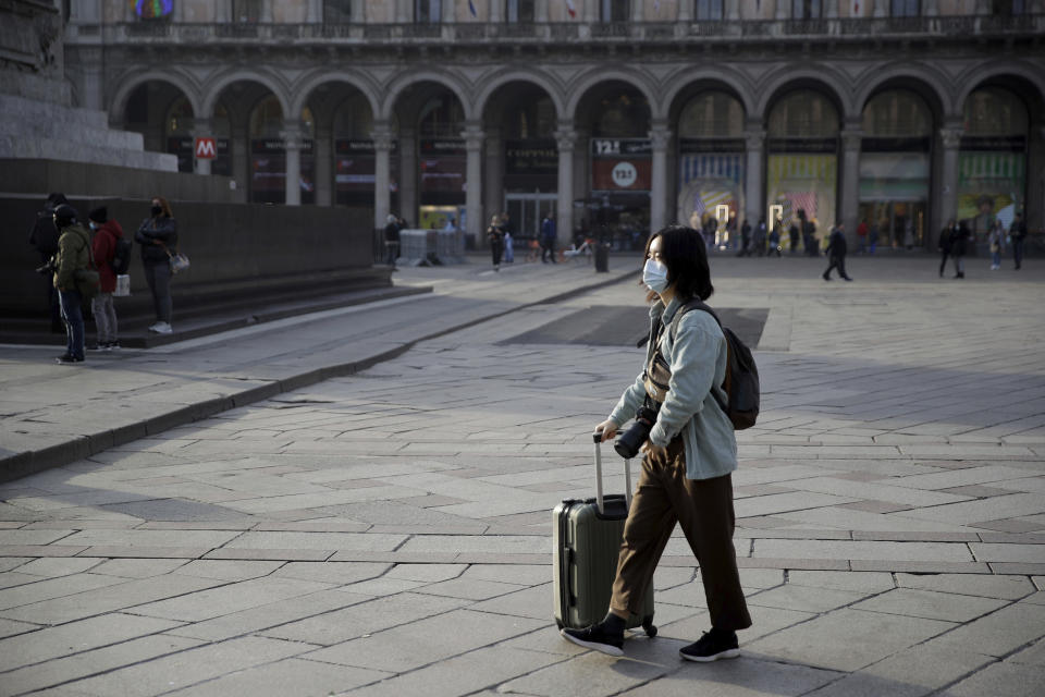 A woman wearing a sanitary mask pushes a trolley in Duomo square, Milan, Italy, Sunday, Feb. 23, 2020. A dozen Italian towns saw daily life disrupted after the deaths of two people infected with the virus from China and a pair of case clusters without direct links to the outbreak abroad. A rapid spike in infections prompted authorities in the northern Lombardy and Veneto regions to close schools, businesses and restaurants and to cancel sporting events and Masses. (AP Photo/Luca Bruno)