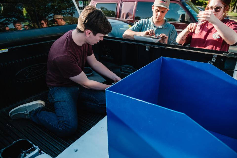 Kent State University at Tuscarawas engineer students Bryce Hoffman, from left, John Chaney and Kylie Miklovic scramble to attempt a last minute fix of their capstone project – a water skimmer intended to collect surface debris at the Tuscora Park Pond in New Philadelphia.