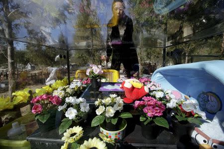 Pet owner Ma Ying cleans the glass covering her dog Liu Dazhuang's tomb, with bathtub, dolls and decoration flowers placed inside, ahead of the Qingming Festival at Baifu pet cemetery on the outskirts of Beijing, China March 27, 2016. REUTERS/Jason Lee