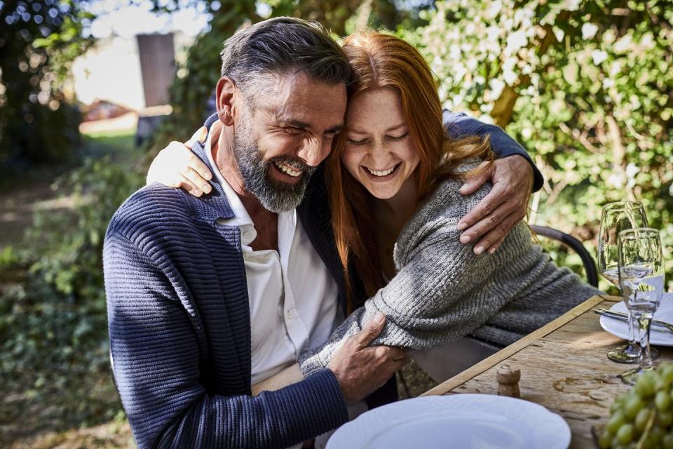 happy father and adult daughter hugging on a garden party