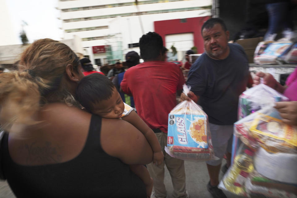 Residents receive donated items in the aftermath of Hurricane Otis, in Acapulco, Mexico, Friday, Nov. 10, 2023. Nearly three weeks after the Category 5 hurricane devastated this Pacific port, leaving at least 48 people dead and the city’s infrastructure in tatters, the cleanup continues. (AP Photo/Marco Ugarte)