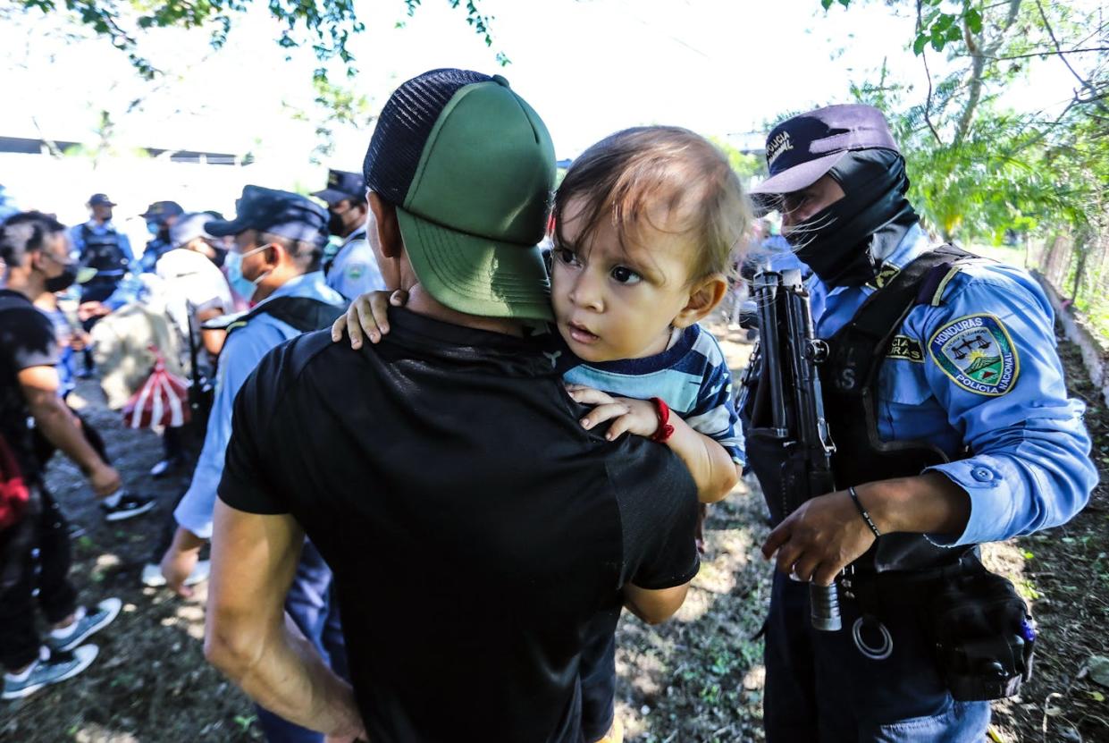 A man with a child shows his identification to police officers at a checkpoint in Honduras as migrants attempt to reach the U.S. <a href="https://www.gettyimages.com/detail/news-photo/man-holding-a-child-shows-his-identification-to-police-news-photo/1237745632" rel="nofollow noopener" target="_blank" data-ylk="slk:Photo by WendelPhoto by WENDELL ESCOTO/AFP via Getty Images;elm:context_link;itc:0;sec:content-canvas" class="link ">Photo by WendelPhoto by WENDELL ESCOTO/AFP via Getty Images</a>