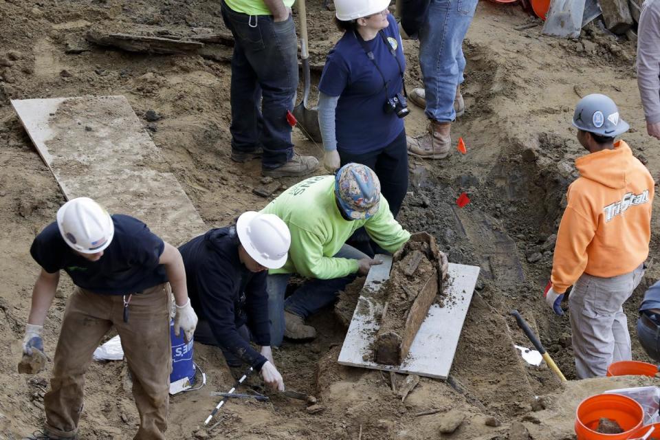 Workers excavate a coffin from a construction site in the Old City neighborhood, Thursday, March 9, 2017, in Philadelphia. Crews working on an apartment building in Philadelphia's historic district got a shock last month when their backhoes started hitting coffins and unearthing fully intact human remains. The site was supposed to be a former burial ground from 1707, and all remains were supposedly exhumed in the 1800s and moved to a different cemetery. (AP Photo/Matt Slocum)