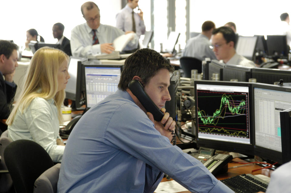 A trader in busy office looks at data on computer screens.