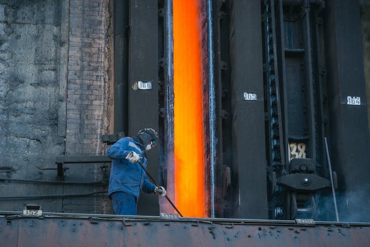 A person loading coking coal into a furnace.