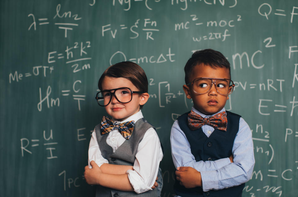 Pictured: Two young boys compare themselves in front of complex maths equation on chalk board. Image: Getty