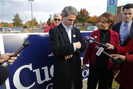 Virginia Republican gubernatorial nominee Ken Cuccinelli checks his watch to discern how many more hours the polls will be open as he talks to reporters after casting his ballot at a polling place at Brentsville High School in Nokesville, Virginia, November 5, 2013. Also pictured is his wife Teiro Cuccinelli (2nd R). REUTERS/Jonathan Ernst