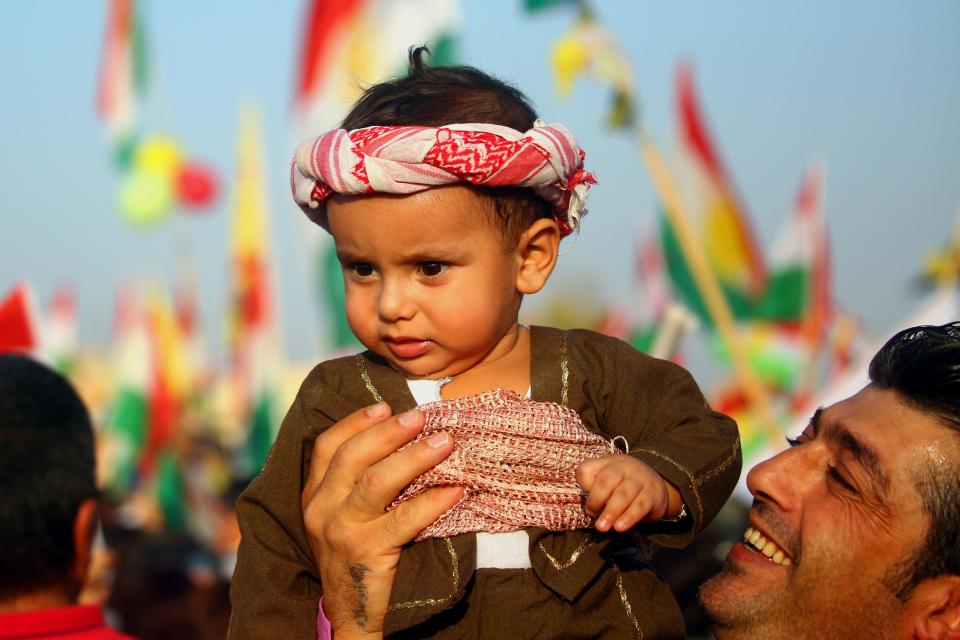 <p>A Syrian Kurdish man holds a child dressed in a traditional outfit as he takes part in a rally in the northeastern Syrian city of Qamishli on Sept. 15, 2017, in support of an independence referendum in Arbil. (Photo: Safin Hamed/AFP/Getty Images) </p>