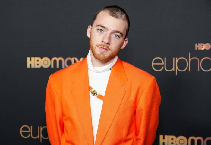 A closeup of Angus in an orange blazer